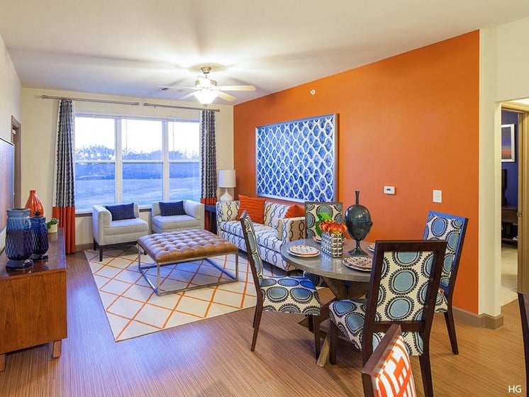 a living room with orange walls and a dining room with a table and chairs
